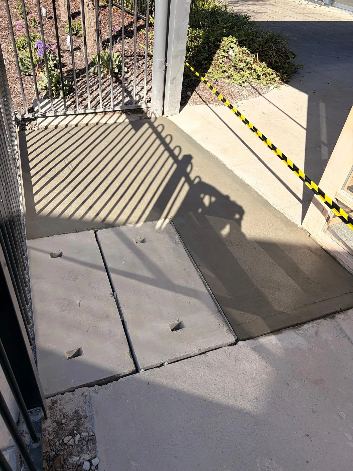 Fresh concrete path poured with a clean finish around the existing pit lids